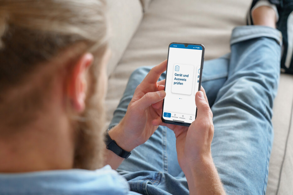 Man lying on sofa and using AusweisApp2 on his smartphone